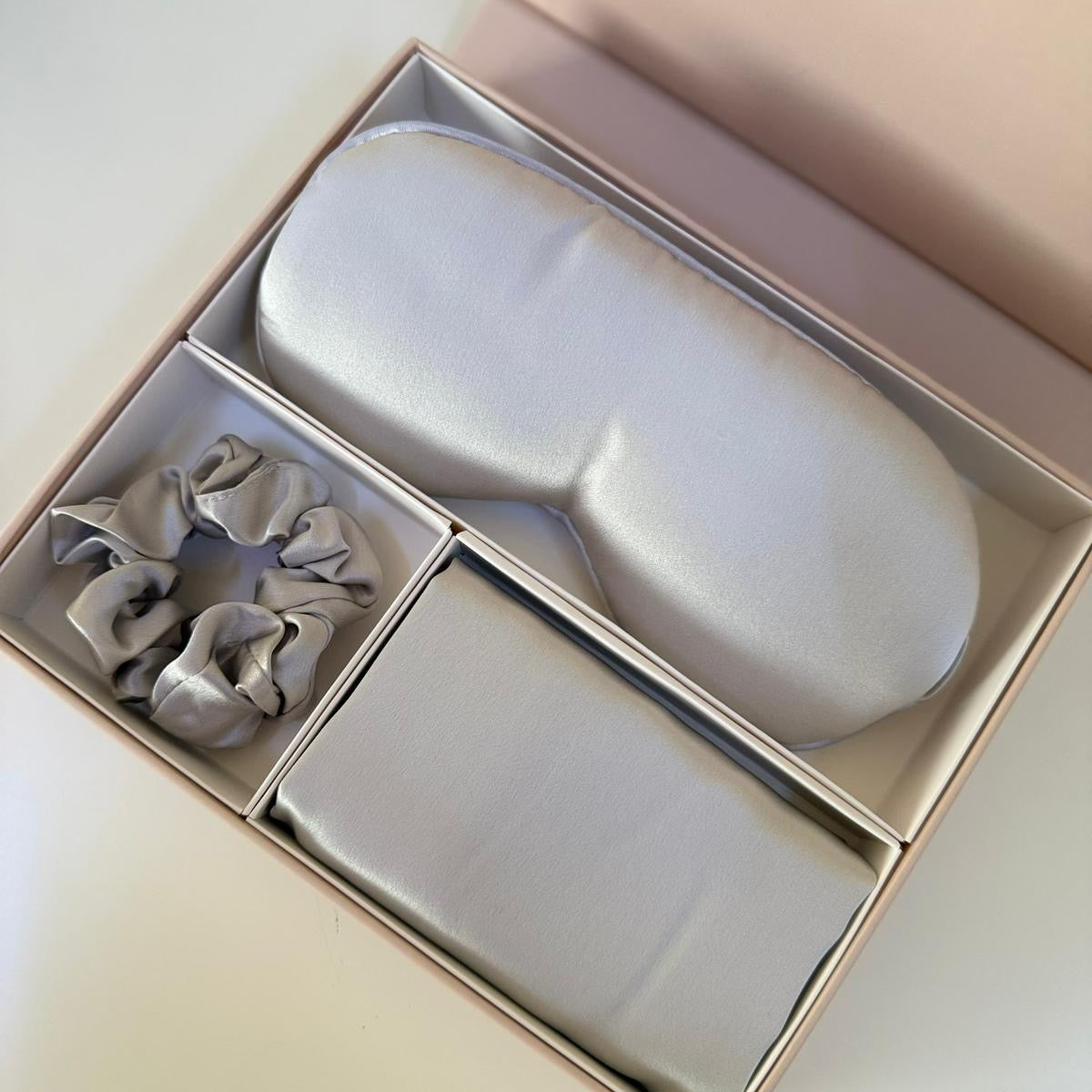 Set of scrunchies and a small white container in a box on a light background