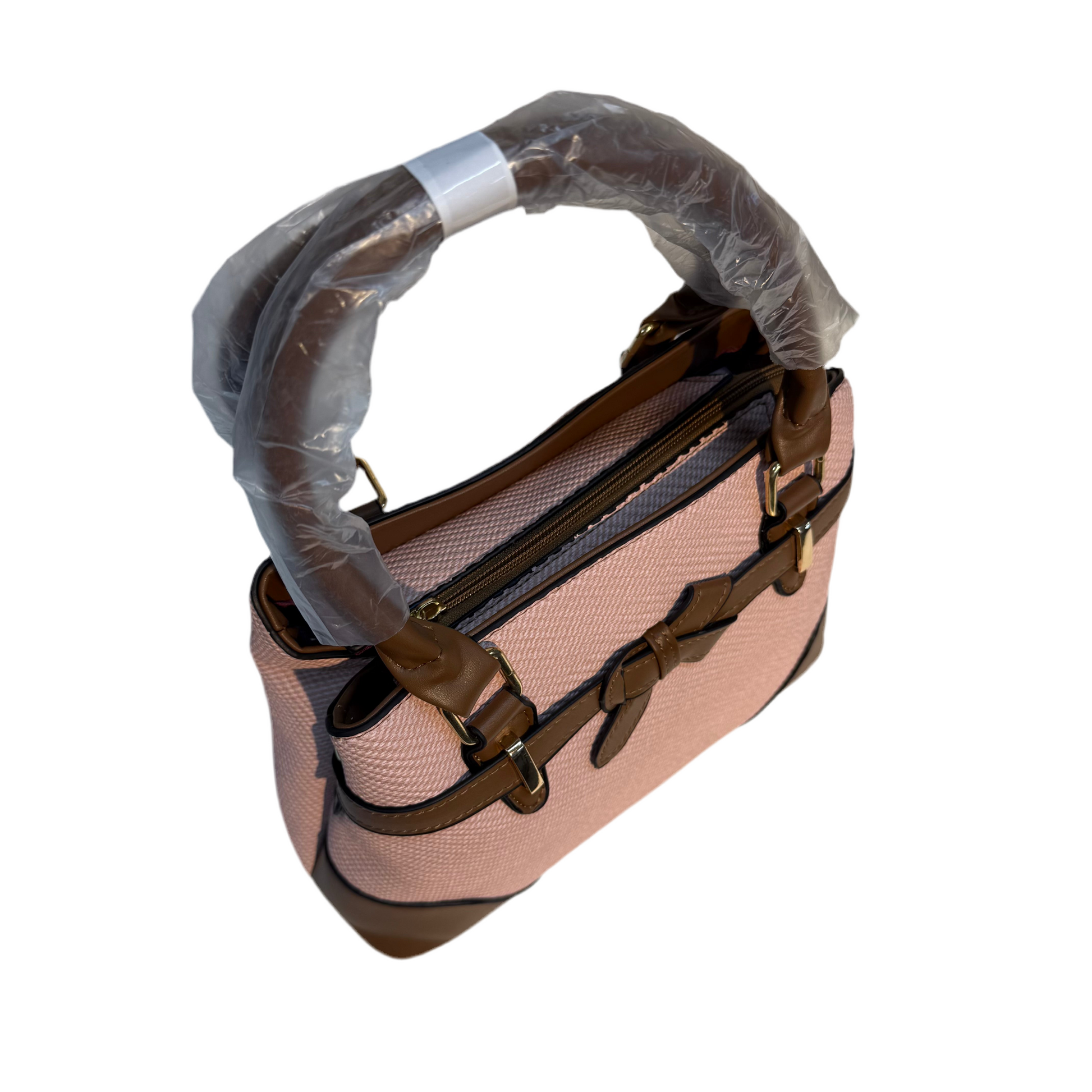 Pink handbag with brown handles and accents, partially covered by plastic wrap on a white background