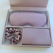 Set of pink eye mask, scrunchie, and pouch in a box on a white background