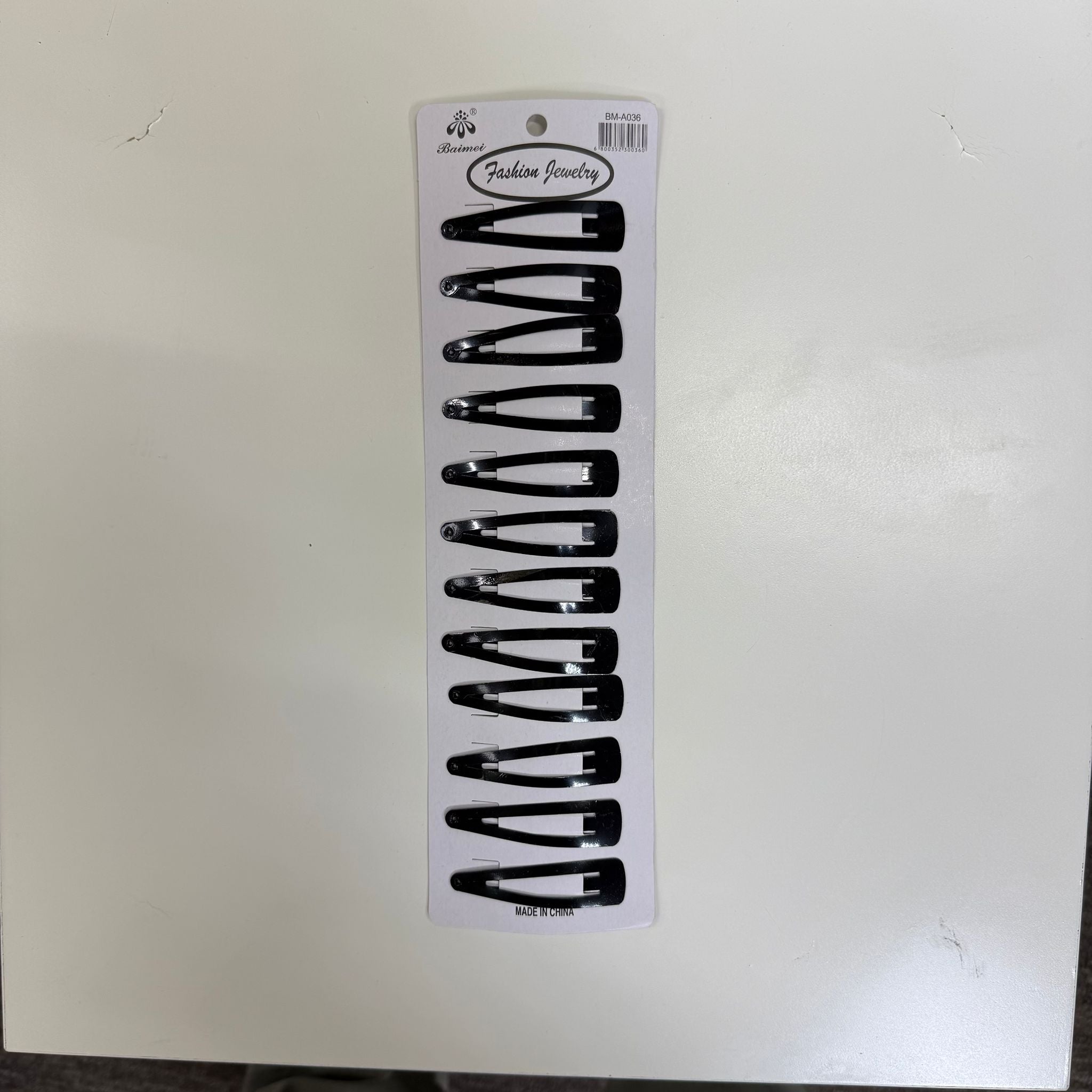 Set of black hair clips on a white card with brand logo