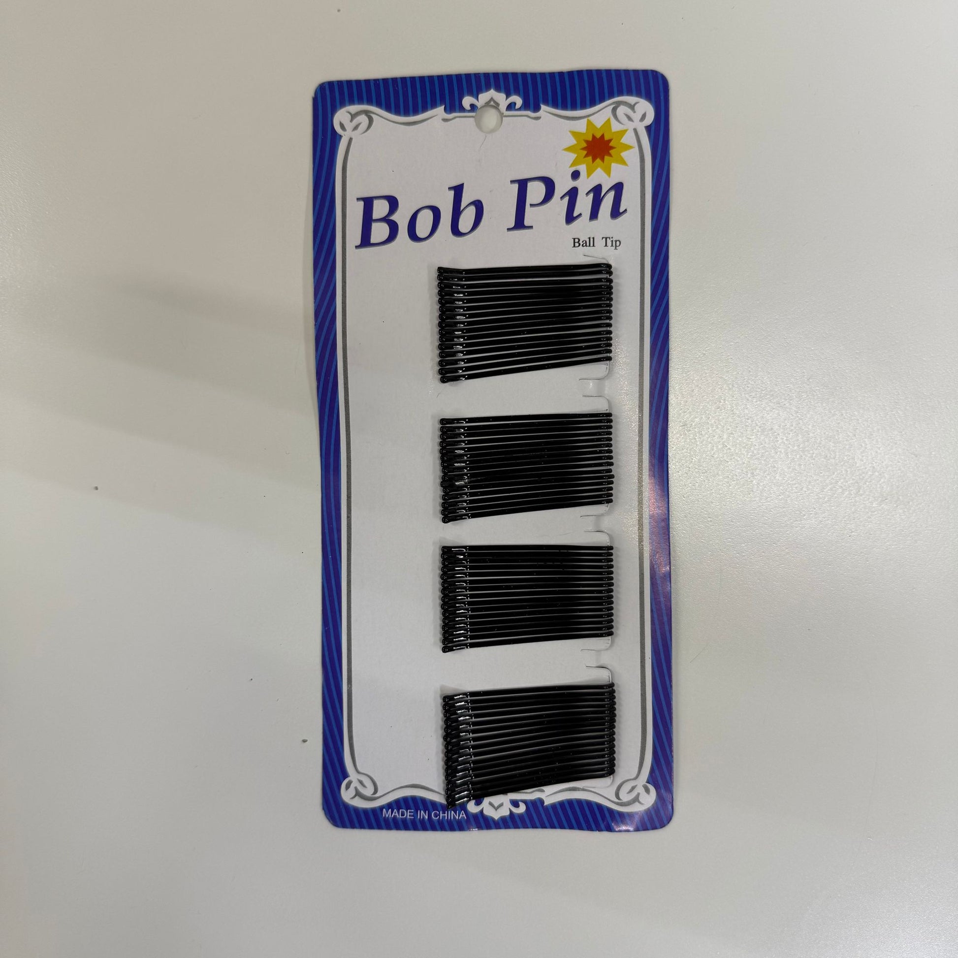 Pack of black hair pins with a blue and white label on a white background